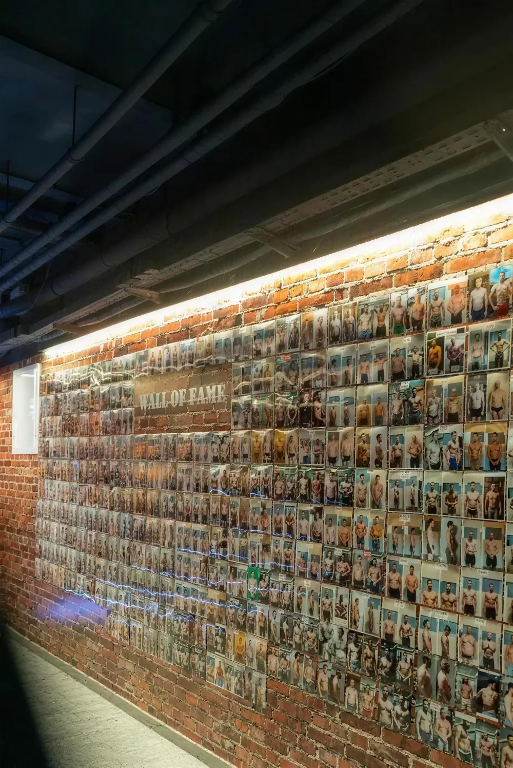 Wall of Fame: beleuchtete Backsteinwand mit Fotos von Mitgliedern